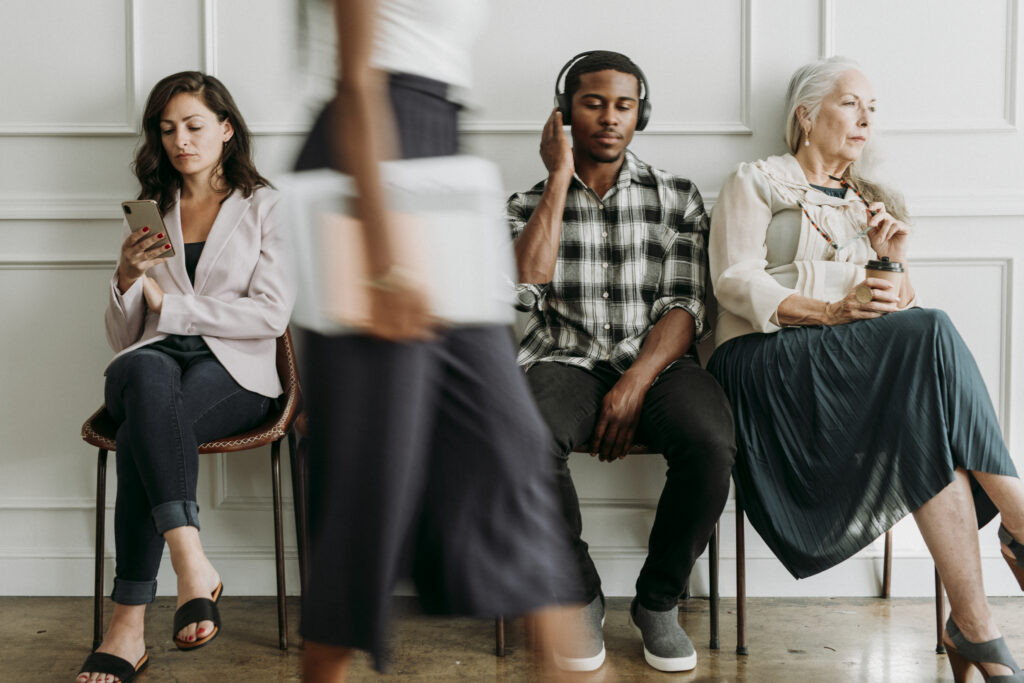 Diverse people sitting by a white wall social listening